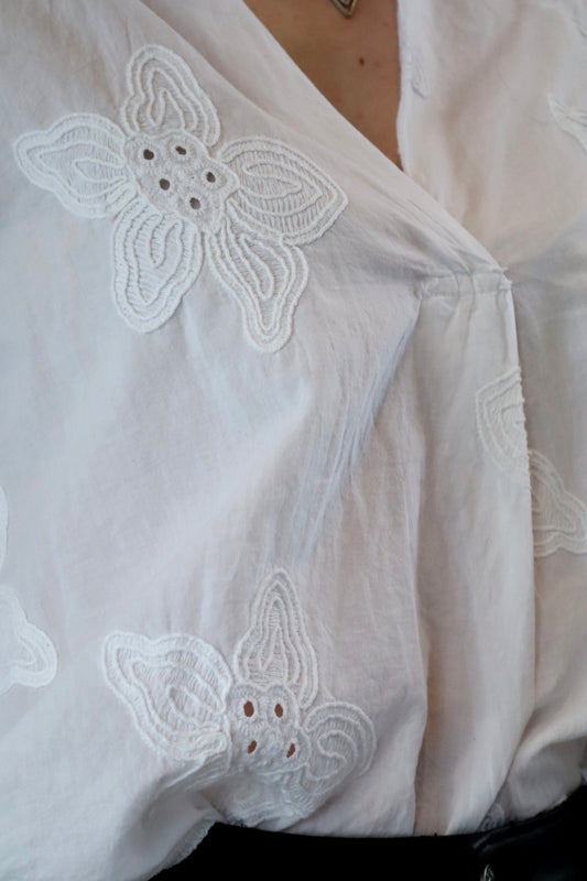 Textures florales : Cette blouse blanche capture l'essence de la beauté naturelle avec ses motifs floraux en relief, offrant un équilibre parfait entre simplicité et sophistication pour une allure élégante et distinguée.